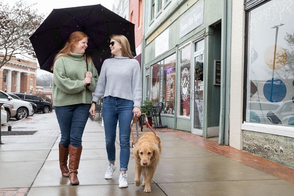 image of Lindsey Chambers walking in rain with a woman and service dog