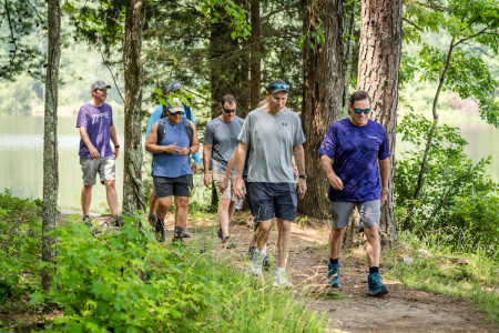 Truist teammate Mark Case leads a group of people on a hike in the woods near a lake