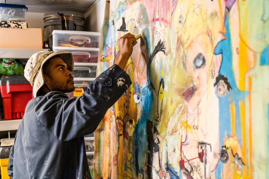 Justin Ellis, a Charlotte, NC artist, works on a vibrant multi-media piece in his studio