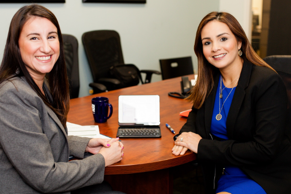Image of two women smiling at camera in a conference room