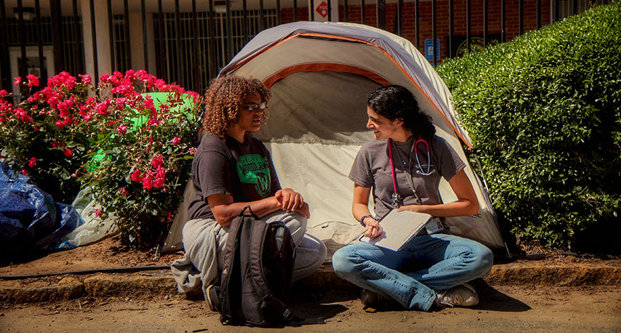 Image of two nurse and patient outside of tent